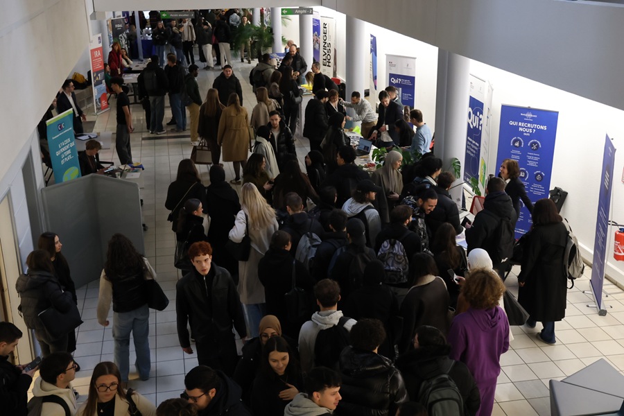 Des étudiants se renseignant sur des stands de partenaires disposés dans l'atrium